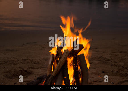 Lagerfeuer am sandigen Strand nach Sonnenuntergang Stockfoto