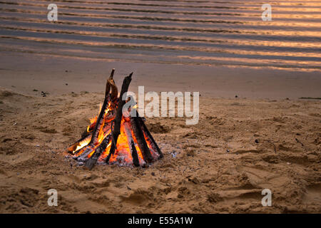 Lagerfeuer am sandigen Strand nach Sonnenuntergang Stockfoto