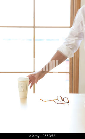 Mann erreicht für Kaffee bei der Arbeit Stockfoto