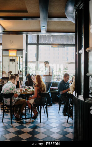 Gruppe von Freunden mit Brunch, Kellner, Bestellannahme, Fenster mit Hochhaus im Hintergrund. Stockfoto