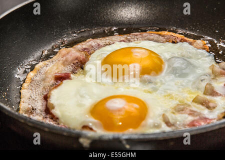 Spiegeleier und Speck in einer Pfanne erhitzen, Frühstück, Stockfoto