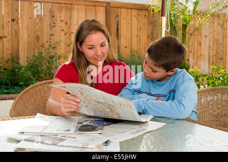 Multi ethnischen, rassischen Vielfalt ethnisch vielfältigen multikulturellen kulturelle Mutter Kind Kinder son10 bis 11 Jahre lesen Zeitung Hinterhof. USA Stockfoto