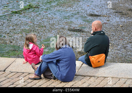 Familie sitzt am Hafen Wand, Brixham, Devon, England, UK Stockfoto
