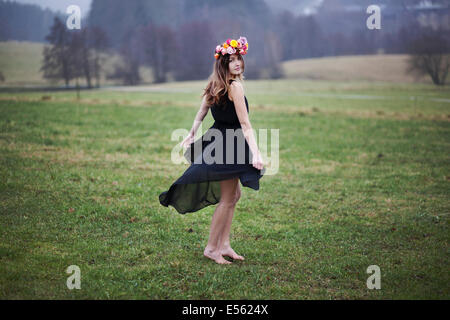 Junge Frau mit Blumen Kranz tanzen auf einer Wiese Stockfoto