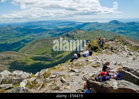 Walkers take a break to admire the view from the summit of Mount Snowdon. Looking southwards over Snowdonia to Cardigan Bay Stockfoto