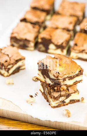 Süße Brownies gestapelt auf weißem Papier und Holz Stockfoto