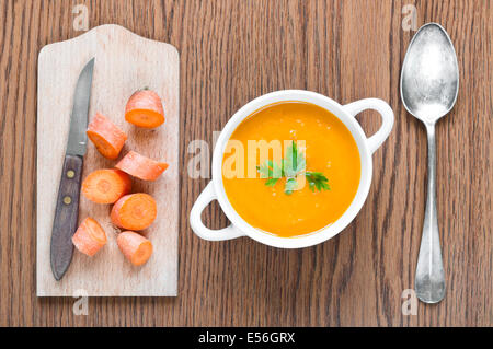 Karottensuppe mit frischen Karotten, Löffel und Messer hautnah Stockfoto