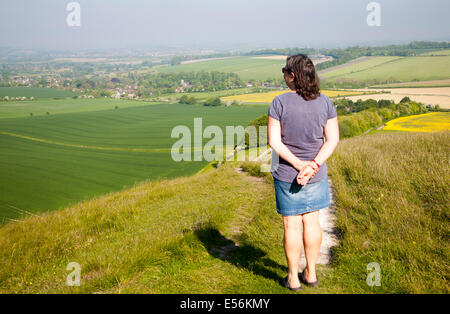 Frau stehend auf steilen Kreide Böschung Hang Cherhill Down, Wiltshire, England mit Blick auf das Dorf Cherhill Stockfoto