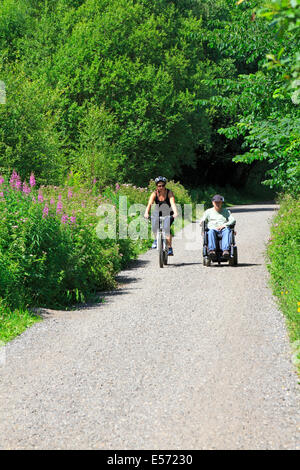 Weibliche Radfahrer und ein Mann in einem elektrischen Rollstuhl am Monsal Trail in Upperdale, Derbyshire, Peak District National Park, England, UK. Stockfoto