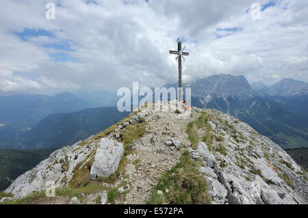 überqueren Sie zwei Frauen sitzen auf dem Gipfel des Berges Daniel vor bewölkt Zugspitze, Lermoos, Österreich Stockfoto