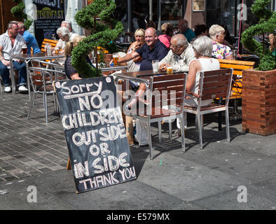 Nur Erwachsene in Liverpool, Merseyside, Großbritannien. Juli 2014. Kinder haben keinen Zutritt zum Essen im Freien im Sommer  Essen im Freien bei heißem Wetter im Freien mit Ausnahme von Kindern. Entschuldigen Sie das Schild „keine Kinder draußen oder drinnen“ in einem Café am Williamson Square, Liverpool, da die Gäste in einer kinderfreien Zone ein Getränk und Essen genießen. Stockfoto