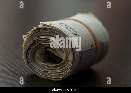 Rolle des UK Geld auf einem schwarzen Hintergrund mit einem Gummiband um Stockfoto