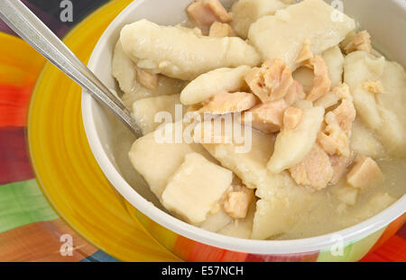 Ganz in der Nähe Blick auf Huhn und Knödel Suppe in eine Schüssel auf einen bunten Teller mit Löffel. Stockfoto