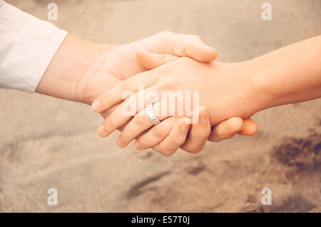 Halten die Hände am Strand, ein neu Brautpaar zeigt ihren Verlobungsring Stockfoto