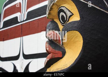 Indianer Totempfahl Gesicht, eingefangen von Seite mit Langhaus Wand im Hintergrund (lackiert) Stockfoto