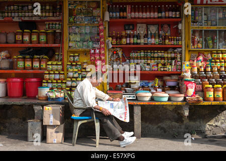 UDAIPUR, Indien, 3. Januar 2014 - Shop Besitzer liest eine Zeitung vor seinem Geschäft in den Straßen von Udaipur, Indien. Stockfoto