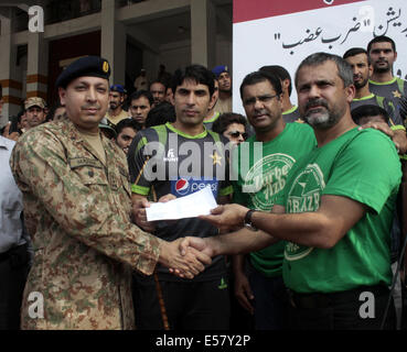 Lahore, Bannu, Pakistan. 22. Juli 2014. Pakistanische Cricket-Team-Manager und Chef-Selektor Moin Khan (R) und Team-Kapitän Misbah-ul-Haq (C) posieren für ein Foto, wie sie einen Scheck zu einer pakistanischen Armee offiziell in Richtung Spenden für Zivilisten, die durch eine militärische Operation gegen militante in Nord-Waziristan vertrieben wurden zu gehen, wie sie in Bannu, im östlichen Pakistan Lahore am 22. Juli 2014 versandt werden. Bildnachweis: Jamil Ahmed/Xinhua/Alamy Live-Nachrichten Stockfoto