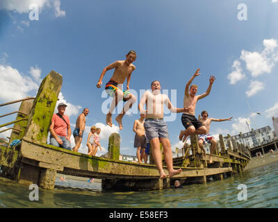 Aberystwyth, Wales, UK. 23. Juli 2014.  Da Temperaturen zu einer Spitze in der hohen 20er Jahre Celsius klettern, finden Gruppen von Kindern im Sommerurlaub einen Weg der cooling-off bei heißem Wetter durch einen Sprung ins Meer bei Aberystwyth an der Westküste Wales UK.  Die Hitzewelle wird voraussichtlich ein weiteres paar Tage dauern, mit Projekt Temperaturen fast bis 30c in etwa landeinwärts Orte Photo Credit: Keith Morris/Alamy Live-Nachrichten Stockfoto