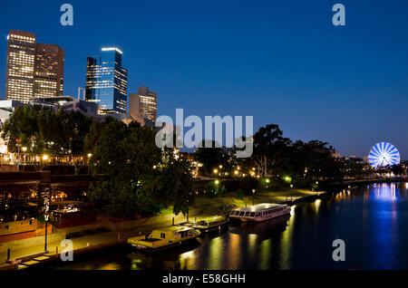 Blick über den Yarra River zeigen die Nacht Skyline der Innenstadt mit einem Riesenrad blau beleuchtet. Stockfoto