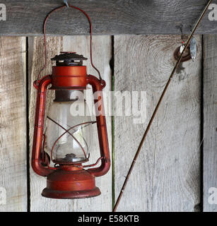 Rote Laterne an rauen Holzhütte Wand mit Angel und Haken in der Nähe Stockfoto