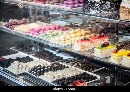 Eine Konditorei-Schaufenster mit einer Auswahl an Kuchen, Pralinen und Macarons in Kentish Town, London Stockfoto