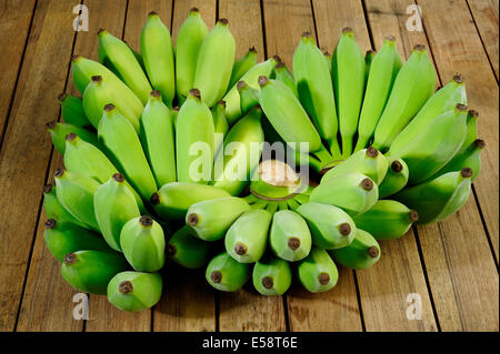 grüne Bananen auf hölzernen Hintergrund Stockfoto