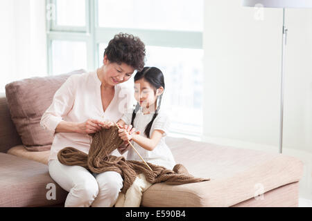 Glückliche Großmutter und Enkelin stricken im Wohnzimmer