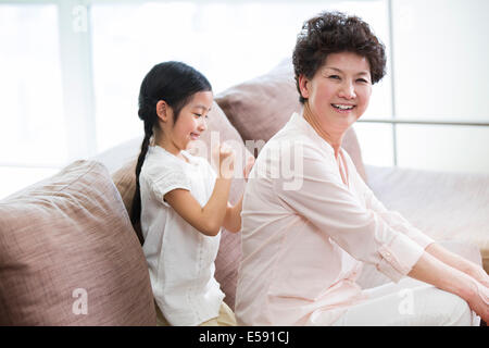 Niedliche Mädchen massieren Großmutter zurück Stockfoto