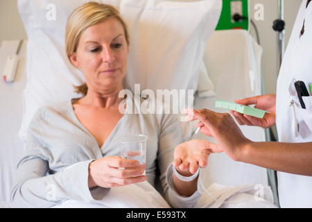 Krankenschwester, die Pille zu Patienten am Krankenbett geben Stockfoto