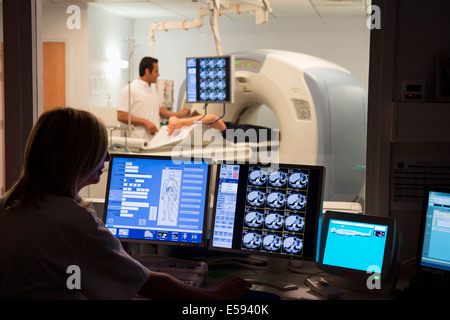 Ärztin untersucht Scan auf Computer mit Patienten auf MRI-Scanner im Hintergrund Stockfoto
