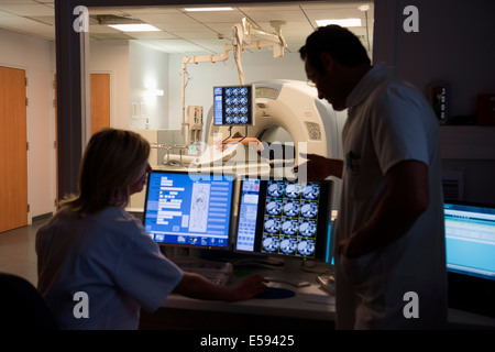 Ärzte untersuchen Scannen auf Computer mit Patienten auf MRI-Scanner im Hintergrund Stockfoto