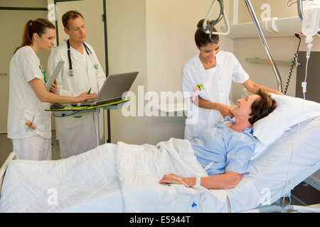 Ärzteteam behandelnde Patientin am Krankenhausbett Stockfoto