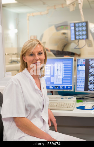 Ärztin, lächelnd in MRI Scan Monitor Arztzimmer Stockfoto