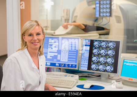 Ärztin, lächelnd in MRI Scan Monitor Arztzimmer Stockfoto