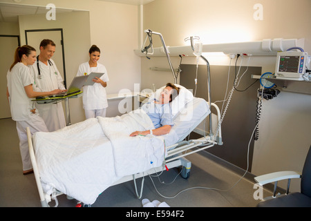 Ärzteteam behandelnde Patientin am Krankenhausbett Stockfoto