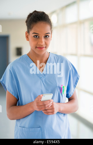 Porträt einer Krankenschwester Textnachrichten mit einem Mobiltelefon Stockfoto