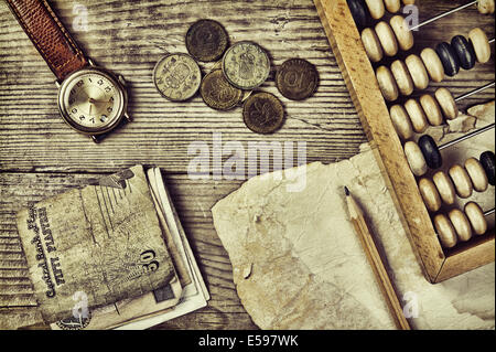 Alte Banknoten und Münzen und Abakus auf einem Holztisch Stockfoto