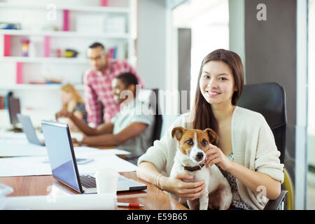 Frau Petting Hund im Büro Stockfoto