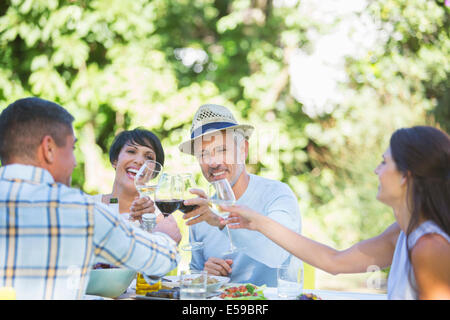 Freunde, die einander am Tisch im freien Toasten Stockfoto