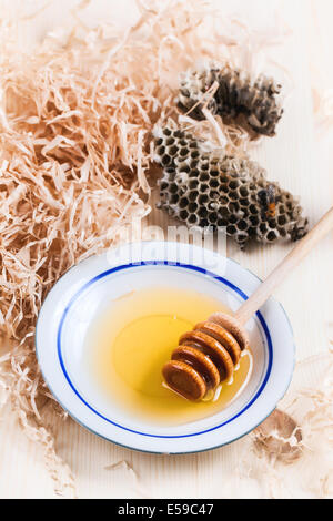 Teller mit Honig mit wilden Waben und Biene über Holztisch Stockfoto