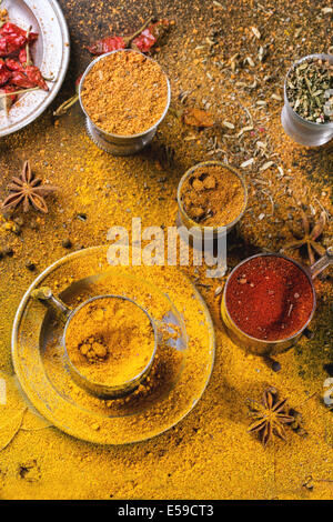 Satz von Gewürzen Pfeffer, Kurkuma, Anis, Koriander in Vintage Metallschalen über gelbe Curry-Pulver. Ansicht von oben. Stockfoto