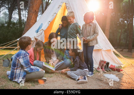 Lehrer und Schüler lesen auf Campingplatz Stockfoto