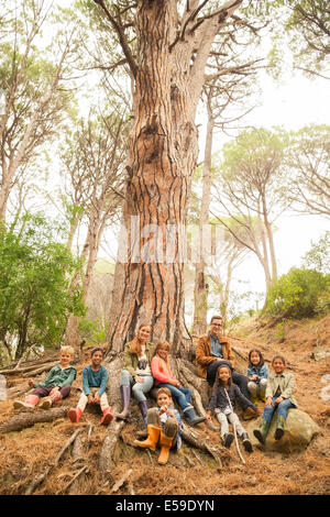 Schüler und Lehrer sitzen auf Baum im Wald Stockfoto