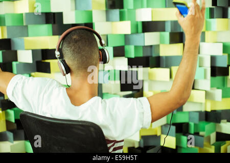 Mann, anhören von MP3-Player im Sessel Stockfoto