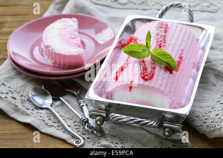 Erdbeer-Vanille-Kuchen-Roll-Eis mit Minze und Beerensauce Stockfoto