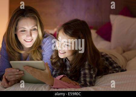 Mutter und Tochter mit digital-Tablette auf Bett Stockfoto