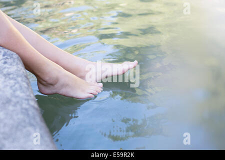 Frau, die Füße im Teich eintauchen Stockfoto