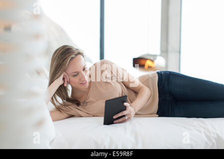 Frau mit digital-Tablette auf Bett Stockfoto