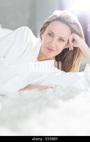 Frau im Bademantel auf Bett Stockfoto