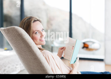 Frau im Sessel lesen Stockfoto